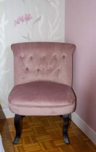 une chaise rose dans un coin de chambre dans l'établissement Chticabane, à Taintrux