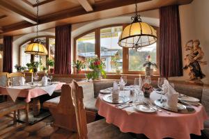 a dining room with two tables and a chandelier at Hotel Bergheimat in Schönau am Königssee