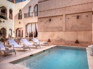 una piscina con sedie a sdraio accanto a un edificio di Riad Passali a Marrakech
