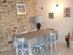a dining room table with chairs and a stone wall at Maison de Pêcheurs in Sarzeau