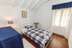 a white bedroom with a bed and a window at Casa da Lagoa in Furnas