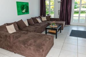 ein Wohnzimmer mit einem braunen Sofa und einem Tisch in der Unterkunft Ferienhof Kolauerhof - Bauernhofurlaub in Grömitz in Grömitz