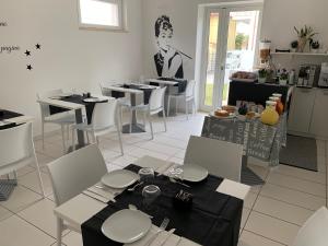 a dining room with tables and white chairs and a waiter at B&B FARAONE in Martinsicuro