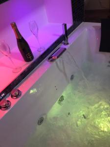 a bath tub with a bottle of wine and wine glasses at Eden spa appartement d’exception in Dijon +22 photos