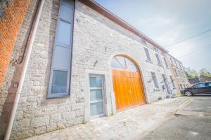 een bakstenen gebouw met een oranje deur erop bij Les soeurs D'Ardennes in Rochefort