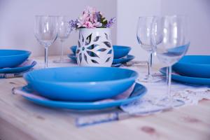 a table with blue plates and glasses and a vase with flowers at Apartments Svijet Mora 2 in Povljana