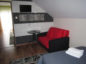 a room with a red chair and a small table at Apartament i pokoje u Roberta in Polańczyk