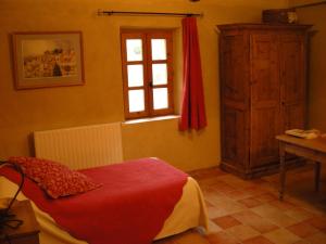 a bedroom with a red bed and a window at La Fontaine in Simiane-la-Rotonde