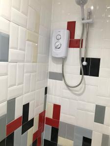 y baño con ducha de azulejos rojos blancos y negros. en Nant Apartment - Ground Floor, en Menai Bridge