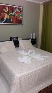 uma cama branca com duas toalhas brancas em Pousada Cardoso em Ipiaú