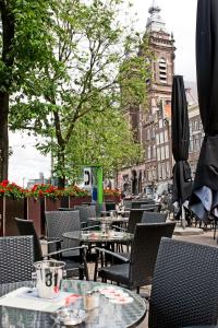una cafetería al aire libre con mesas y sillas y un edificio en Hotel Prins Hendrik, en Ámsterdam