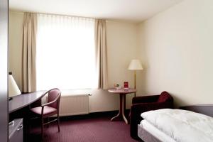 a hotel room with a bed and a desk and a chair at Hotel Erfurter Tor in Sömmerda