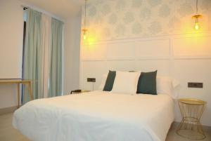 a bedroom with a large white bed with green pillows at Hotel Cedran in Granada