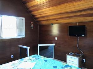 um quarto com uma cama e uma televisão de ecrã plano em Chale Premium Casal e Chale Charming Casal em Mairiporã