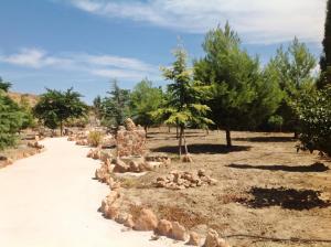 un banc en pierre dans un parc arboré dans l'établissement Cuevas La Granja, à Benalúa de Guadix