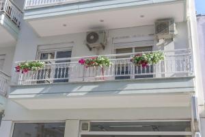 a white building with flowers on a balcony at Sergios Apartments 13 in Alexandroupoli
