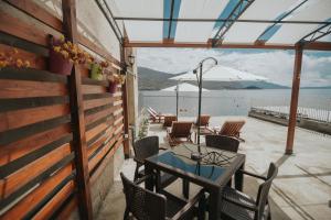 a patio with tables and chairs and a view of the water at Beachfront Apartments Bojadzi in Ohrid