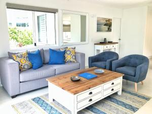 a living room with a couch and two chairs at Regatta Noosa in Noosaville