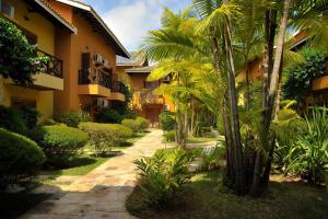 une cour d'un immeuble avec des palmiers et des buissons dans l'établissement Ilha Flat Hotel Suíte Bella - 4207 - Ilhabela, à Ilhabela