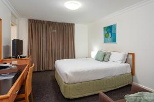 a hotel room with a bed and a desk at Townhouse Hotel in Wagga Wagga