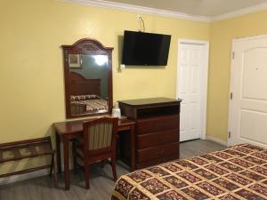 a hotel room with a desk and a mirror at Colony Inn Motel in Bellflower