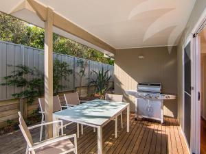 a patio with a table and chairs and a stove at Dunes in Blueys Beach