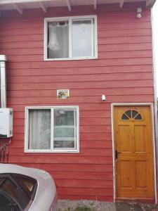 una casa roja con una puerta y dos ventanas en Tres de junio, en Puerto Montt