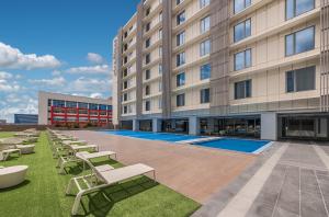 a large building with lounge chairs and a swimming pool at Citadines Bay City Manila in Manila