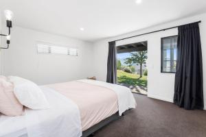 - une chambre blanche avec un grand lit et une fenêtre dans l'établissement Time Out at Lake Wanaka, à Wanaka