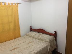 Dormitorio pequeño con cama con cortina amarilla en Departamento Ciro, en San Salvador de Jujuy