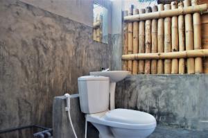 a bathroom with a toilet and a wall with logs at Shim Beach Resort in Arugam Bay