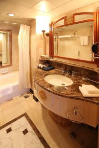 a bathroom with a sink and a mirror and a tub at Huiquan Dynasty Hotel Qingdao in Qingdao