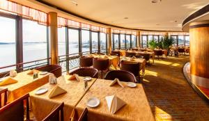 a dining room with tables and chairs and large windows at Huiquan Dynasty Hotel Qingdao in Qingdao