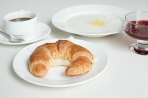 a croissant on a plate on a table with a cup of coffee at Olympica Hotel in Almaty