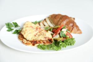 a white plate of food with meat and vegetables at Olympica Hotel in Almaty