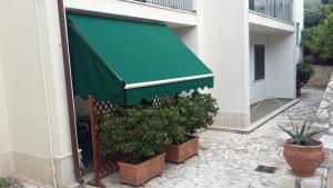 a green awning on a building with potted plants at Residence Chiesiola in Vieste