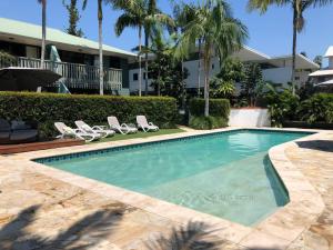 a swimming pool with lounge chairs and a resort at Villa Aitutaki in Byron Bay