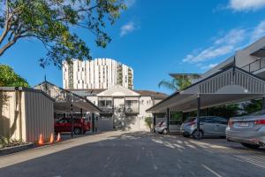 un estacionamiento con un gran edificio blanco en el fondo en Benson Court Motel en Brisbane