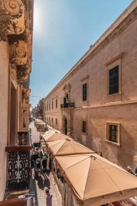 a street with cafes and umbrellas in an old building at Valletta Collection - GB Suites in Valletta