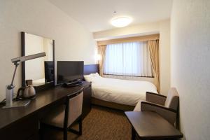 a hotel room with a bed, desk and television at Osaka Dai-ichi Hotel in Osaka