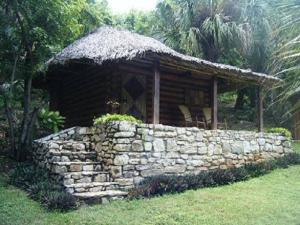 Cabaña de madera con pared de piedra en un campo en Cabañas Sierraverde Huasteca Potosina, en Tamasopo