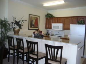 a kitchen with a bar with chairs and a white refrigerator at Ocean Reef 2 bedroom/2 bath! in Panama City Beach