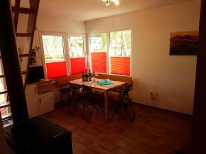 a room with a table and four windows with red blinds at Ferienhaus direkt am Badesee Bungalow 11 Schönsee in Urnshausen