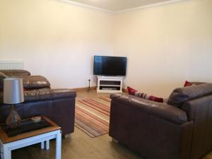 a living room with two couches and a flat screen tv at LAIRDS COTTAGE in Stuartfield