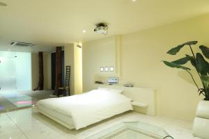 una camera con un letto bianco e una pianta in vaso di C-HOTEL affetto(Adult Only) a Sapporo