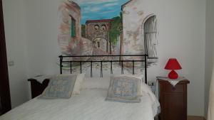 Schlafzimmer mit einem Bett mit Wandgemälde in der Unterkunft Su Cunventu in Muravera