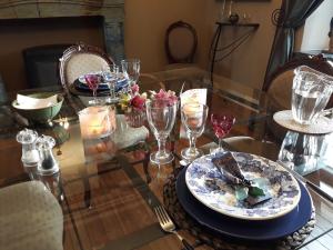 a glass table with a plate of food and wine glasses at Les Glaneuses in Mettet