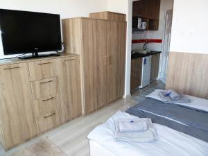 a living room with a flat screen tv and wooden cabinets at Sunrise Apartman in Siófok