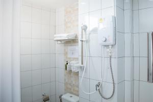 a shower in a white tiled bathroom at Moca Hotel in Bangkok