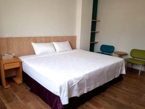 a bedroom with a bed and a table and a chair at Free wind B&B in Taitung City